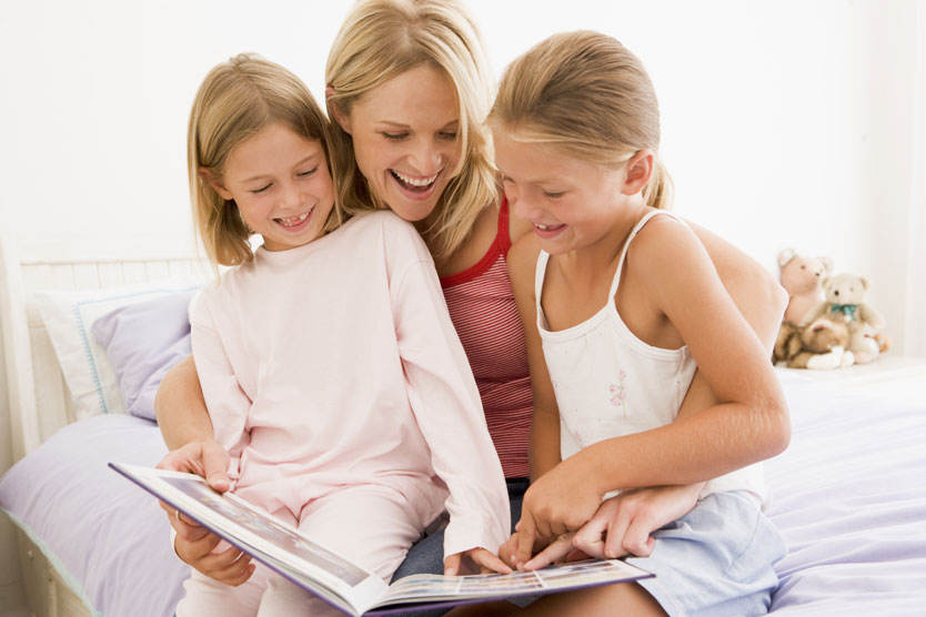 A woman and two girls reading a book.