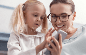 A woman and girl looking at something on the phone.