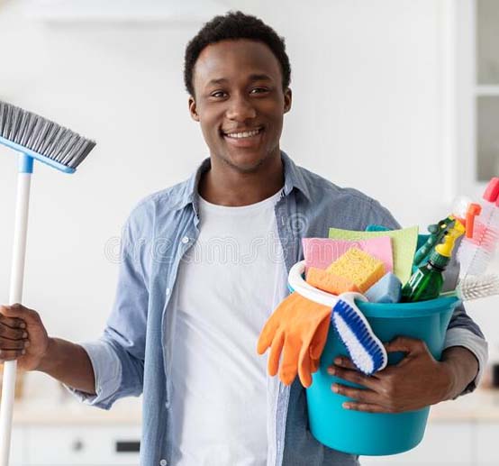 A man holding a cleaning supplies and a broom.