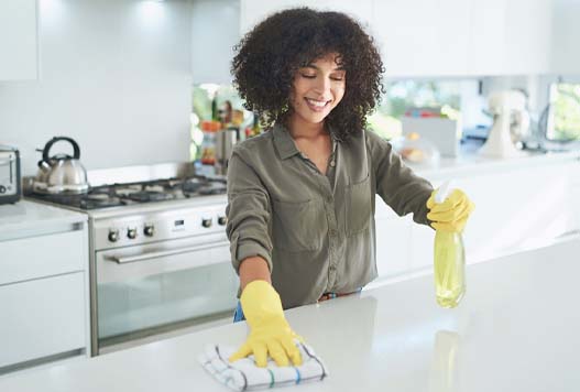 A woman in yellow gloves cleaning the counter.